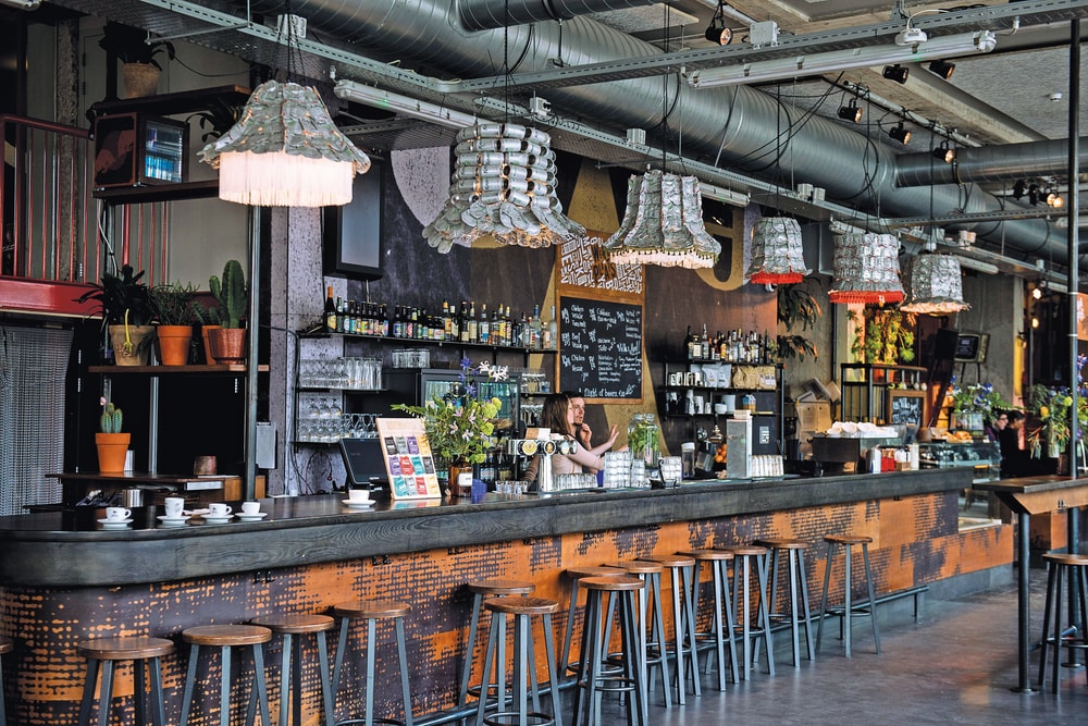 A rustic looking bar in Amsterdam, 2 bar tenders serving drinks.