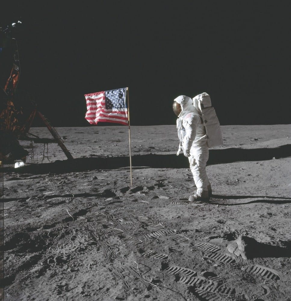 Buzz Aldrin poses beside the deployed United States flag during Apollo 11 extravehicular activity on the lunar surface. The lunar module (LM) is on the left, and the footprints of the astronauts are visible in the soil of the moon. Neil Armstrong took this photo with a 70mm Hasselblad lunar surface camera. While Armstrong and Aldrin descended in the Eagle LM to explore the moon’s Sea of Tranquility region, Michael Collins remained with the command and service module Columbia in lunar orbit. NASA