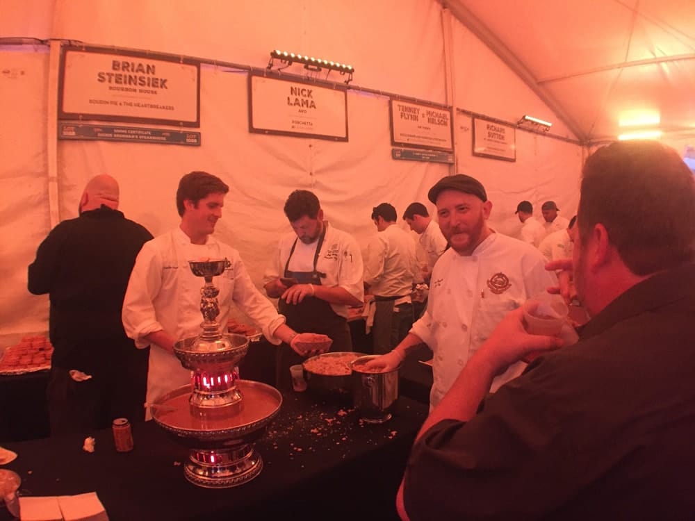 Chefs and guests enjoying food under a tent at the Boudin Bourbon & Beer 2016 charity event in New Orleans, Louisiana