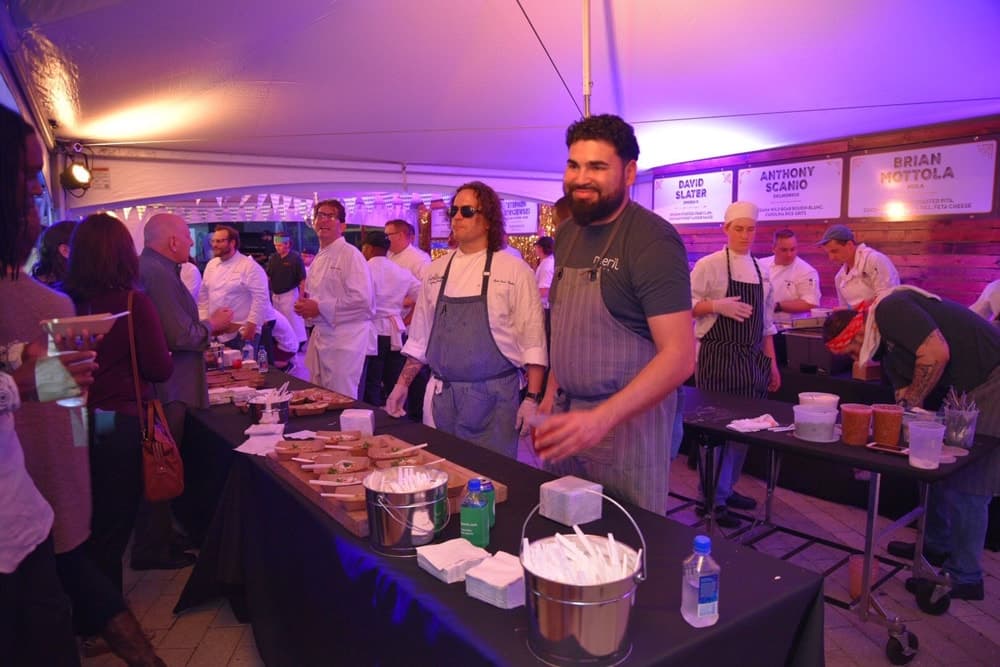 Chefs and guests enjoying food under a tent at the Boudin Bourbon & Beer 2016 charity event in New Orleans, Louisiana
