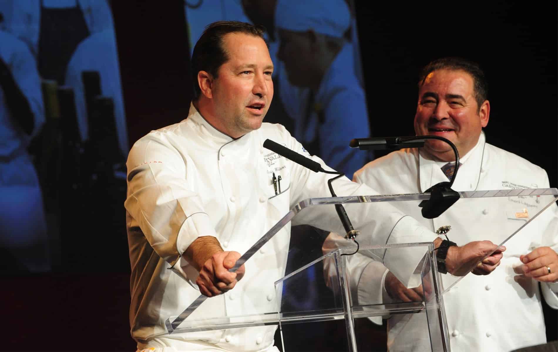 Male chef and Emeril Lagasse speak with guests at the Emeril Lagasse Foundation’ Carnivale du Vin gala and charity wine auction