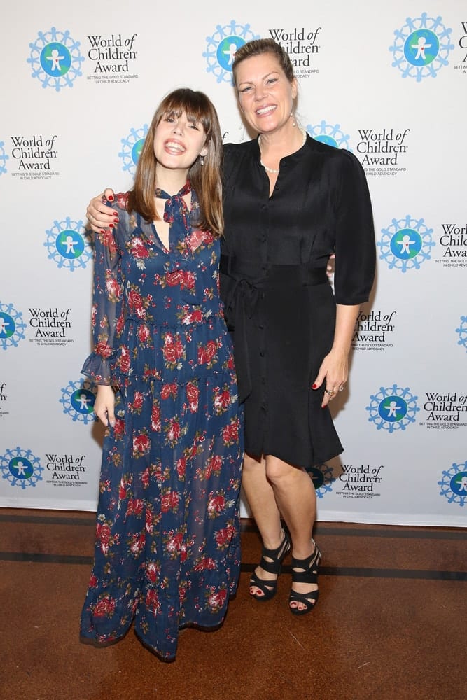 Claire Wineland and Melissa Nordquist pose for a picture in front of the step and repeat banner. The step and repeat banner has a white background with the World of Children Award logo repeated.