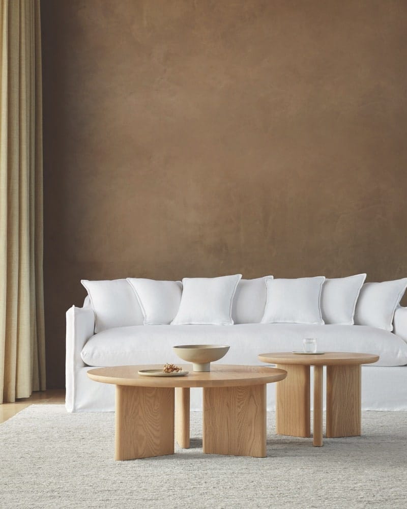 A white couch and brown side tables 