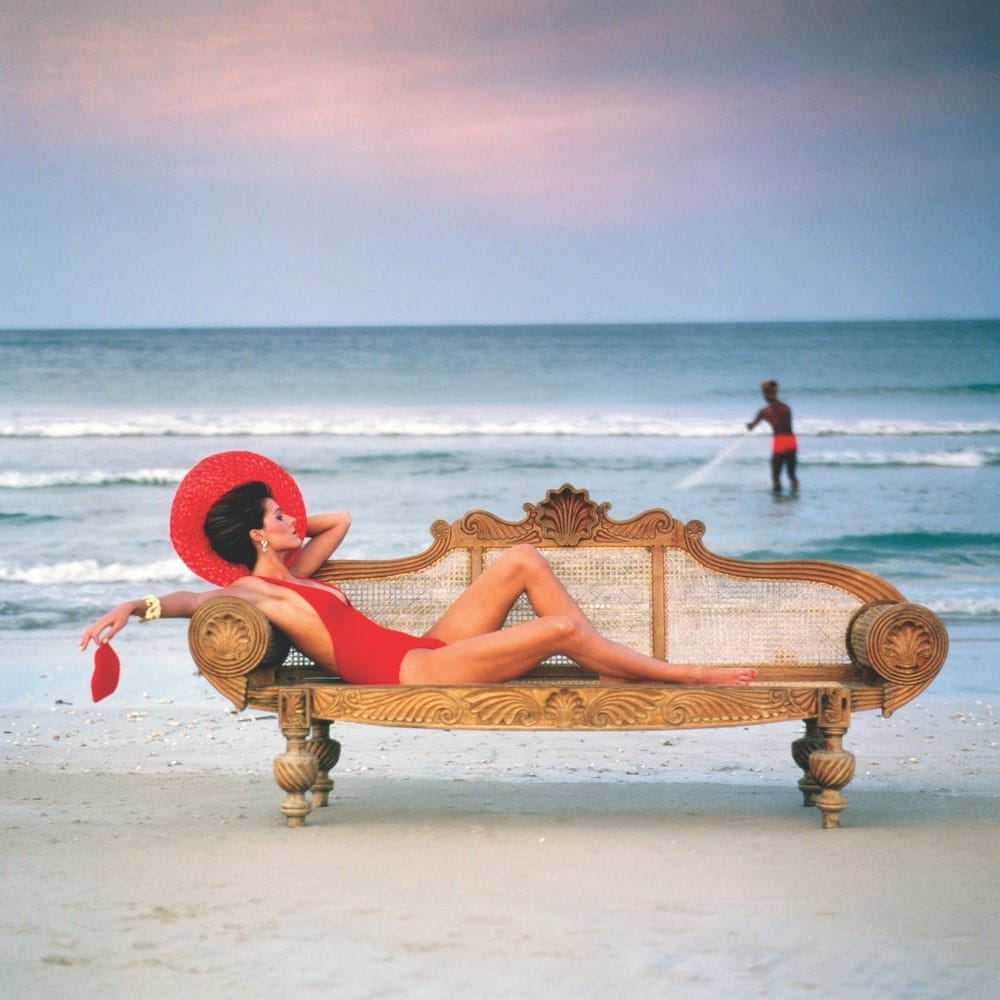 Photo of a girl laying on a bench on the beach by Norman Parkinson