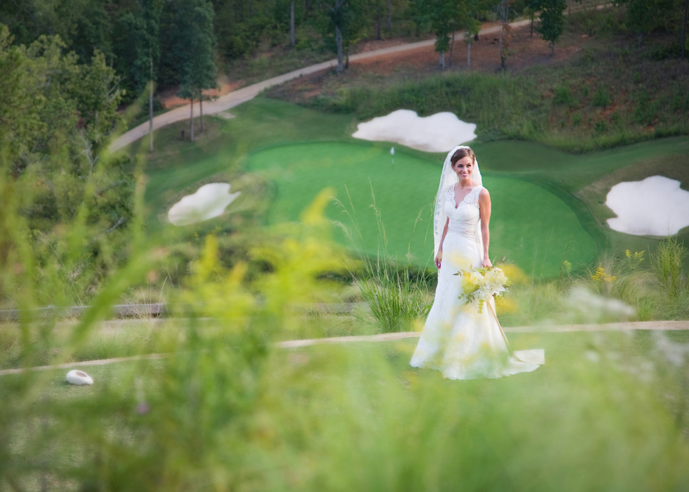 Bride standing on golf green at Vaughn and Tim Spanjer wedding Hamilton Place at Pursell Farms