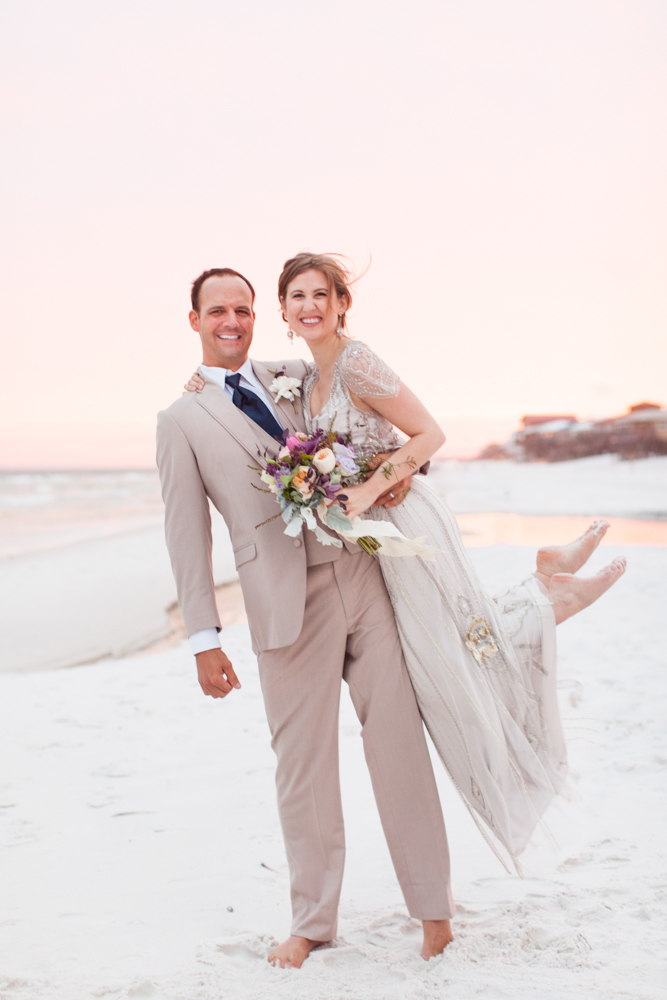 Wedding Event Specialists groom holding up bride while posing on the beach. Photo by Mad Love Weddings