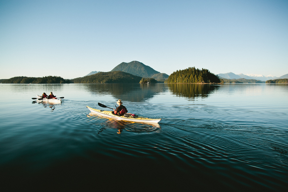 Vacationers kayaking with mountains in the distance in Vancouver Island, Canada