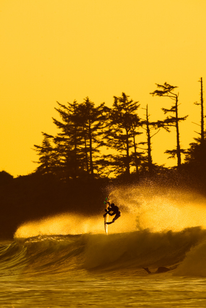 Surfer catching air off of a wave at sunset at Vancouver Island, Canada
