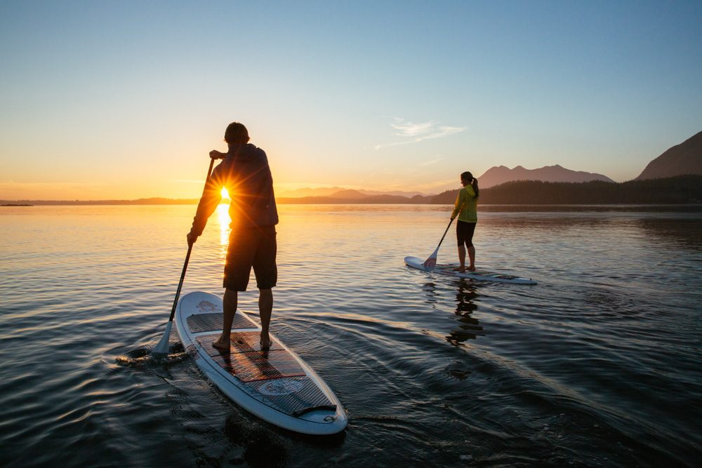 People paddleboarding at sunrise Vancouver Island, Canada