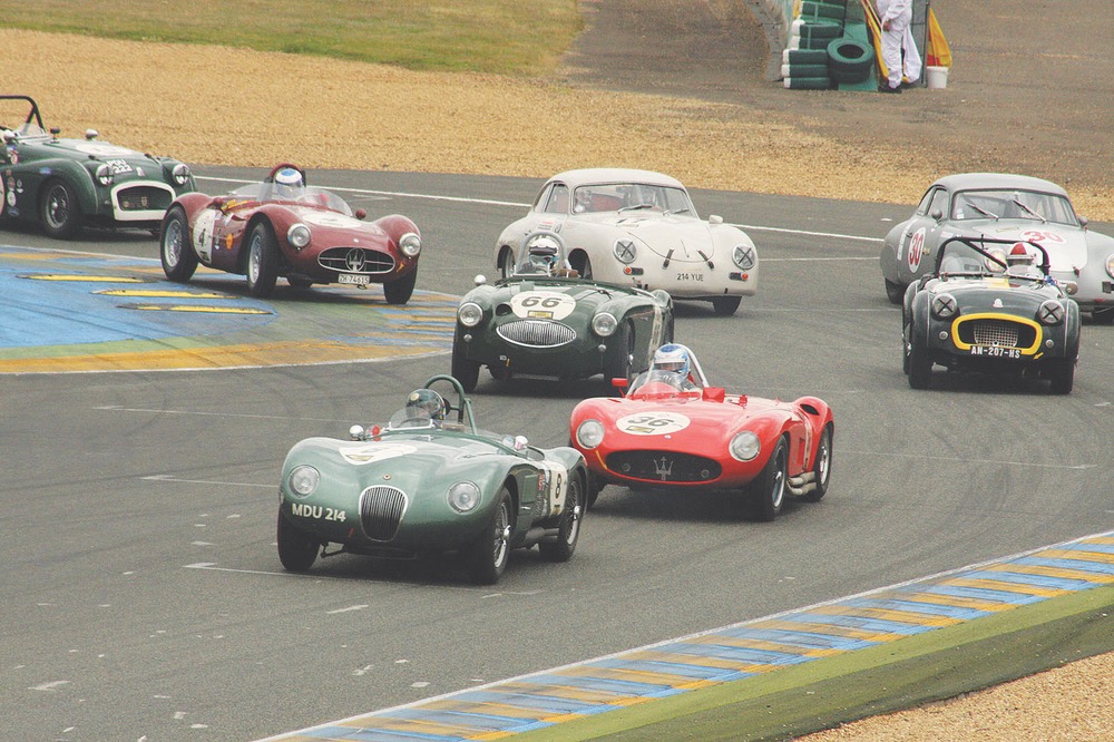 A beautiful, sleek Jaguar C-Type leads this pack of vintage cars from the 1949–1956 grid, including Austin-Healey, Maserati, Porsche, and Triumph