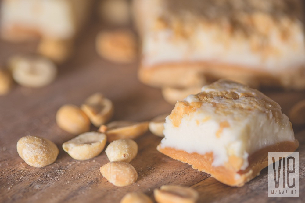 A Few Bars Of EOD Peanut Butter White Chocolate Fudge Plated Next To Peanuts