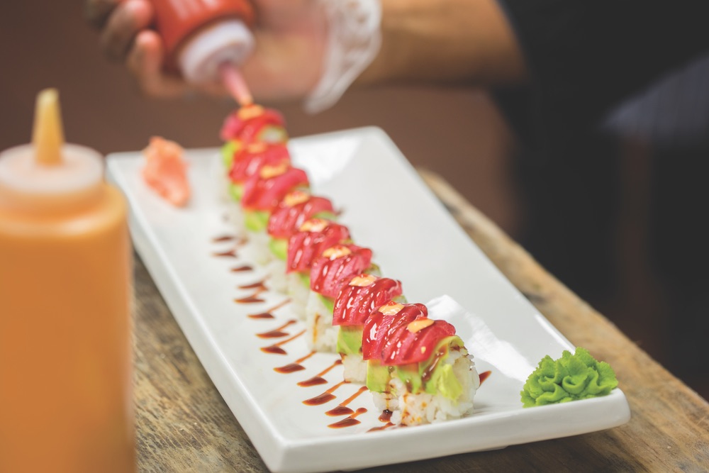 A Handmade Row of Salmon Topped Sushi with Drizzled Eel Sauce and Spicy Mayo