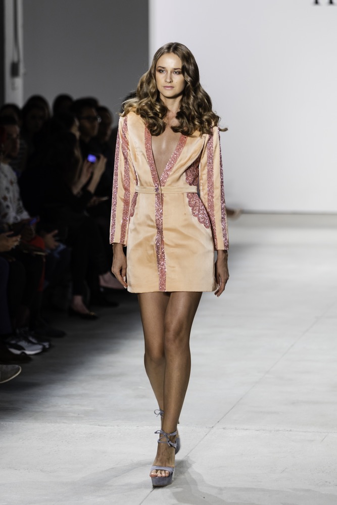 Model Walking Down New York Fashion Week Runway In A Sherbet Orange Deep V Shirt Dress With Rose Colored Trims