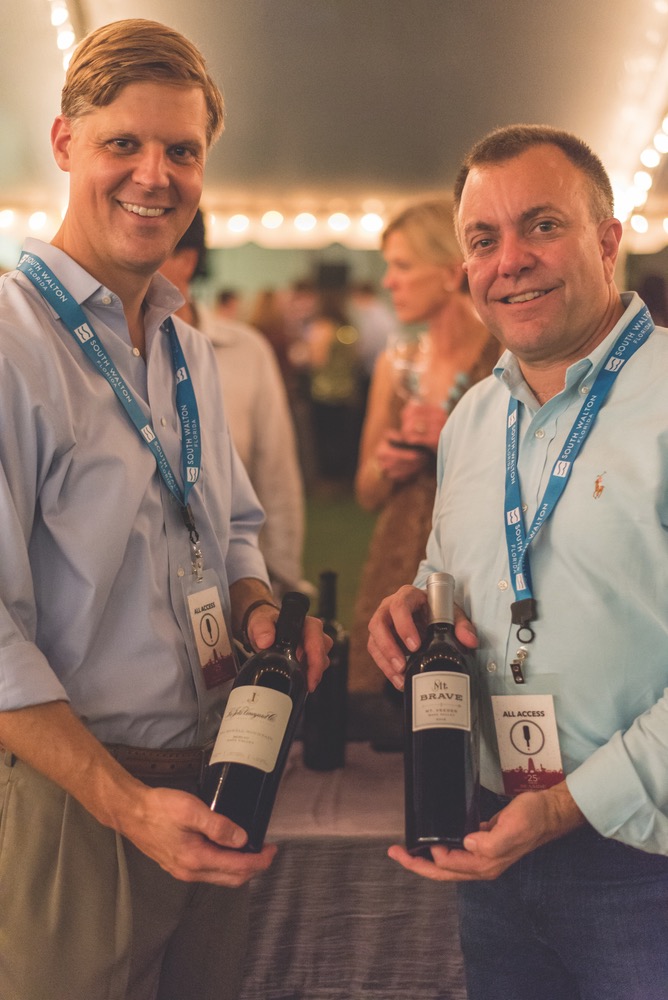 Two Friends Each Holding Up A Bottle Of Wine At The Seeing Red Wine Festival