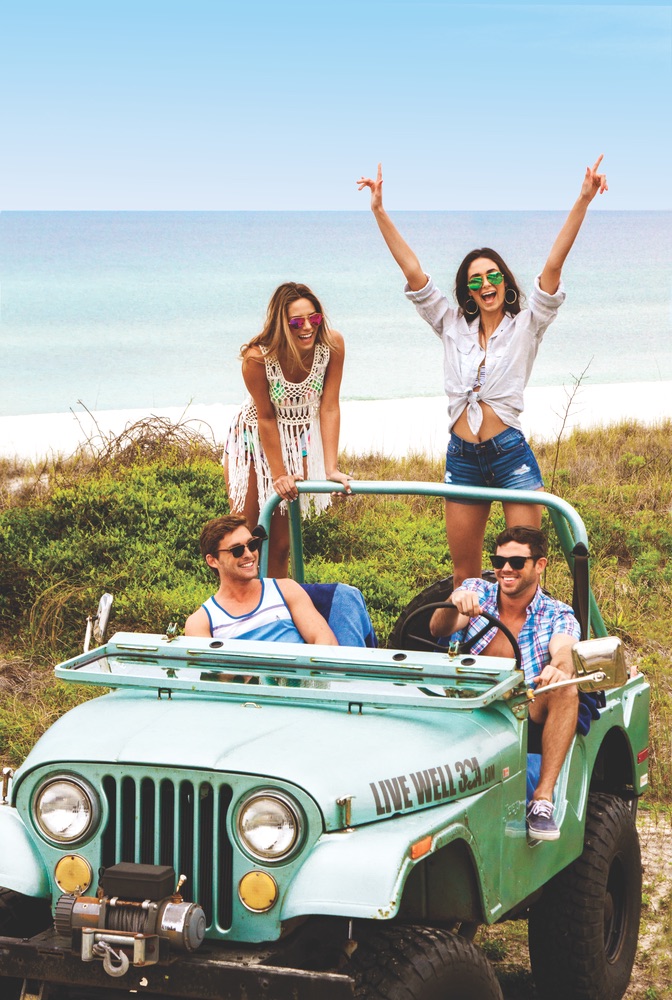 Young adults beach riding in a Jeep