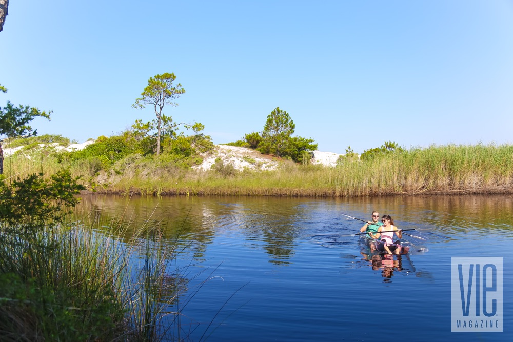 Couple canoeing in Klear Kanoos with sand dunes in the background