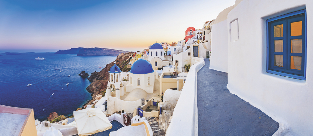 Santorini, Greece with the royal blue waters of the Aegean Sea swimming below Gem of the Aegean Oia sapphire rooftops