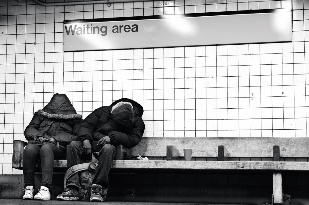 Homeless couple sitting on subway bench sleeping