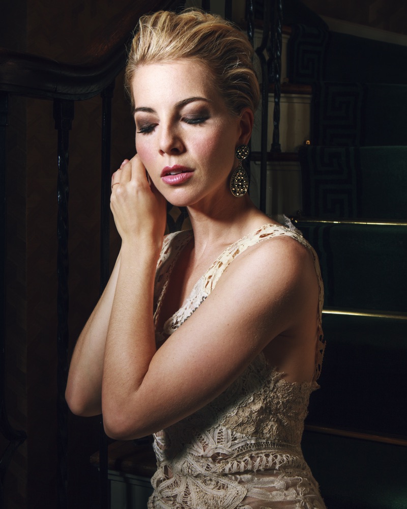 Morgan James putting on her earrings in a stunning Mimi Prober gown The Sophisticate Issue 2016