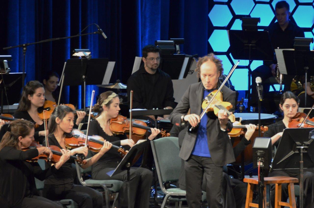 Man leading on violin with youth orchestra