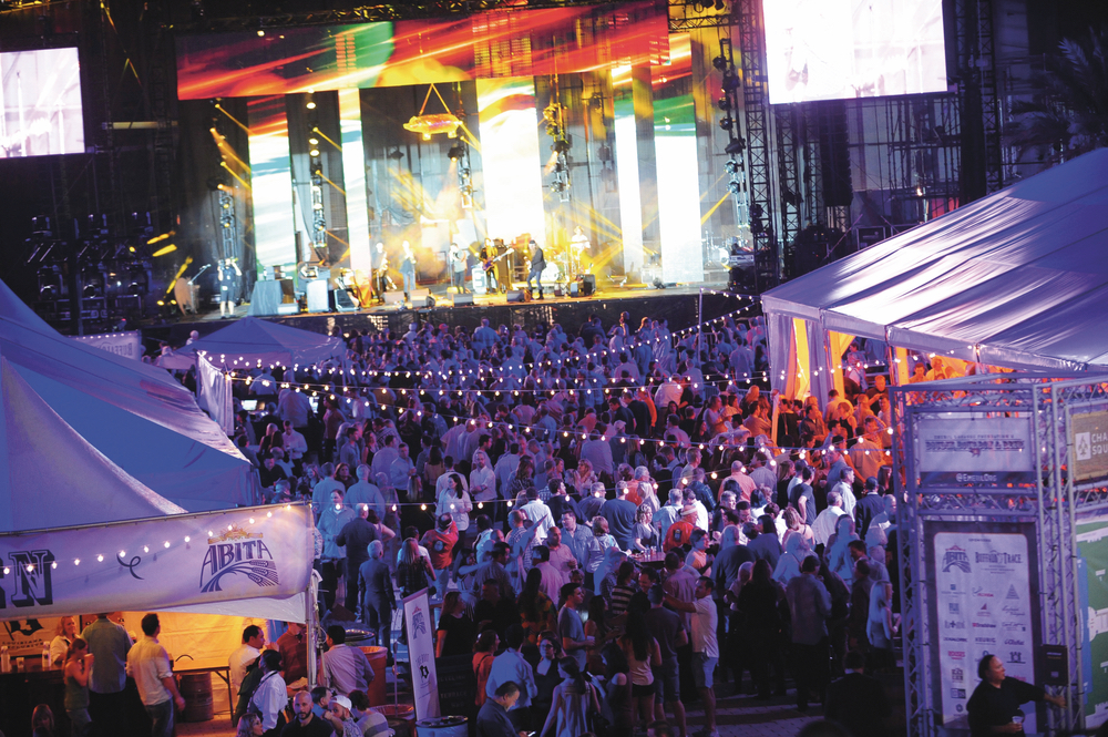 Happy Boudin, Bourbon and Beer attendees enjoy a performance by the Banditos on stage under the disco mirror pig.