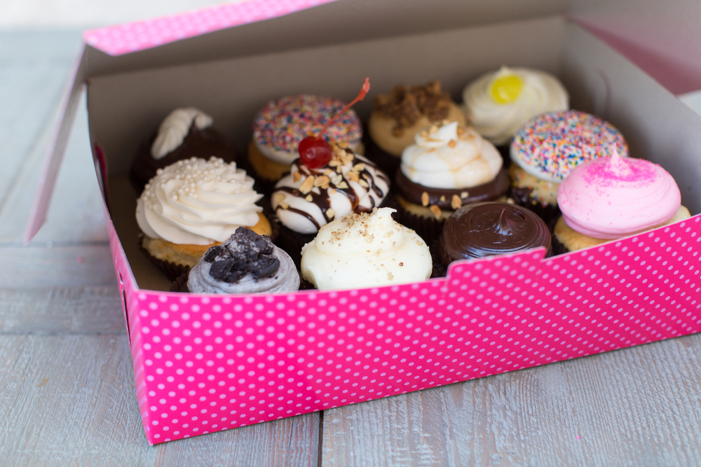 A dozen cupcakes houses in a pink box from Smallcakes Cupcakery and Creamery