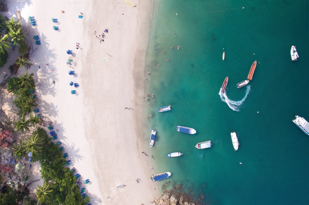 People relaxing on the beach and boats floating in the water represent a typical day on the island of Tortuga, Costa Rica. Chandler Williams, Modus Photography.