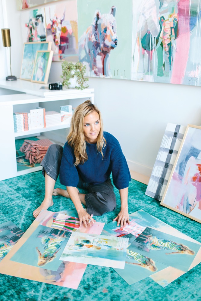 Teil Duncan sitting surrounded by her paintings, photo by Gray Benko