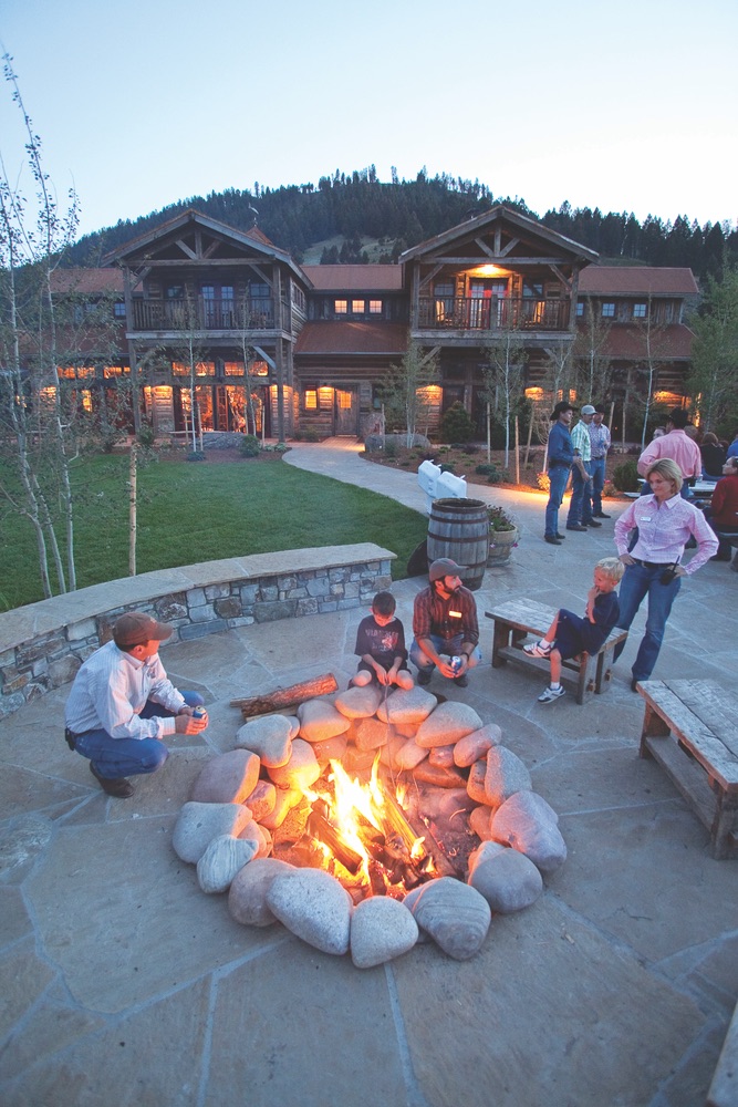 People gather around stone fire pit at The Ranch at Rock Creek