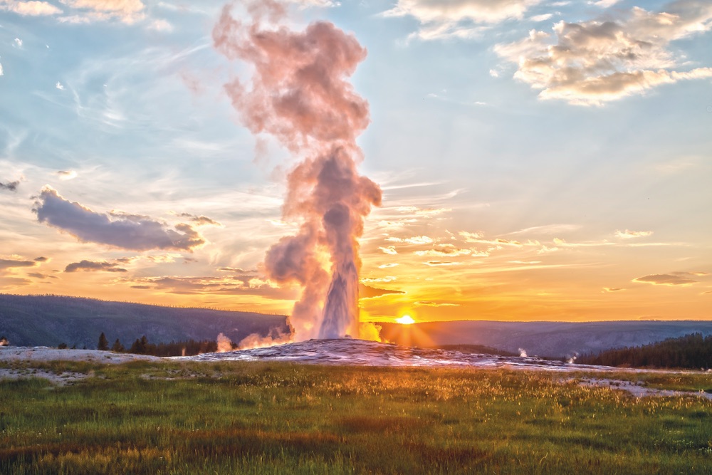 Old Faithful erupting at sunset in Yellowstone National Park—hold on to your cell phones, people!