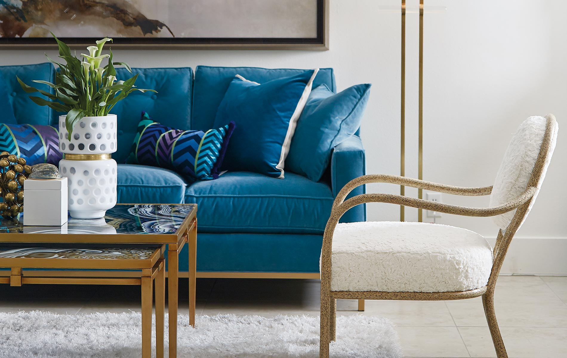 Lovelace Showroom with a gorgeous blue couch gold details white chair Interior Design