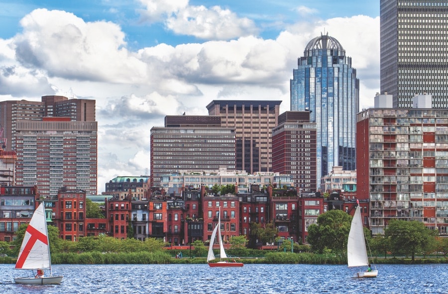 Sailboats cruising along the Charles River with a backdrop of the historic Back Bay neighborhood. VIE Magazine. The Sophisticate Issue