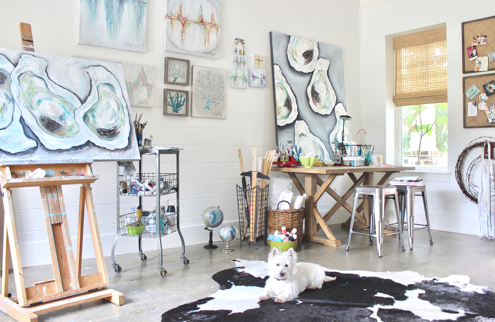 Amy Fogg's art studio with oyster paintings and her white dog