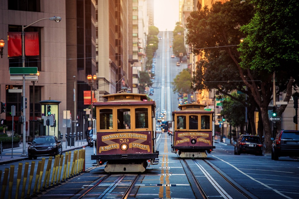 Classic view of historic traditional Cable Cars riding on famous California Street in morning light at sunrise with retro vintage style cross processing filter effect, San Francisco, California