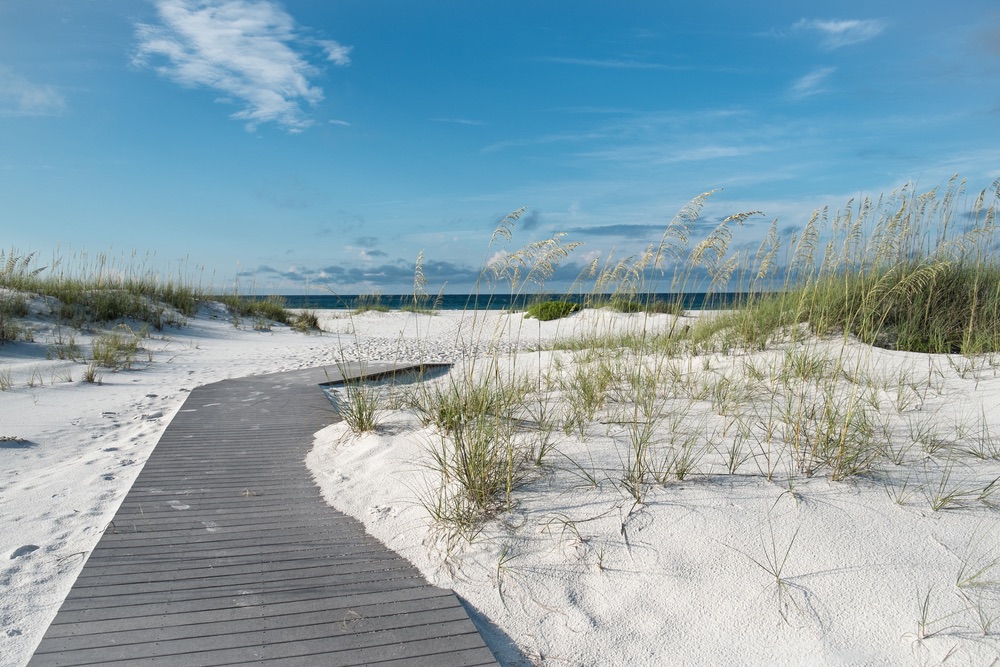 Small rustic boardwalk footpath through snow white sand dunes at a pristine Florida beach