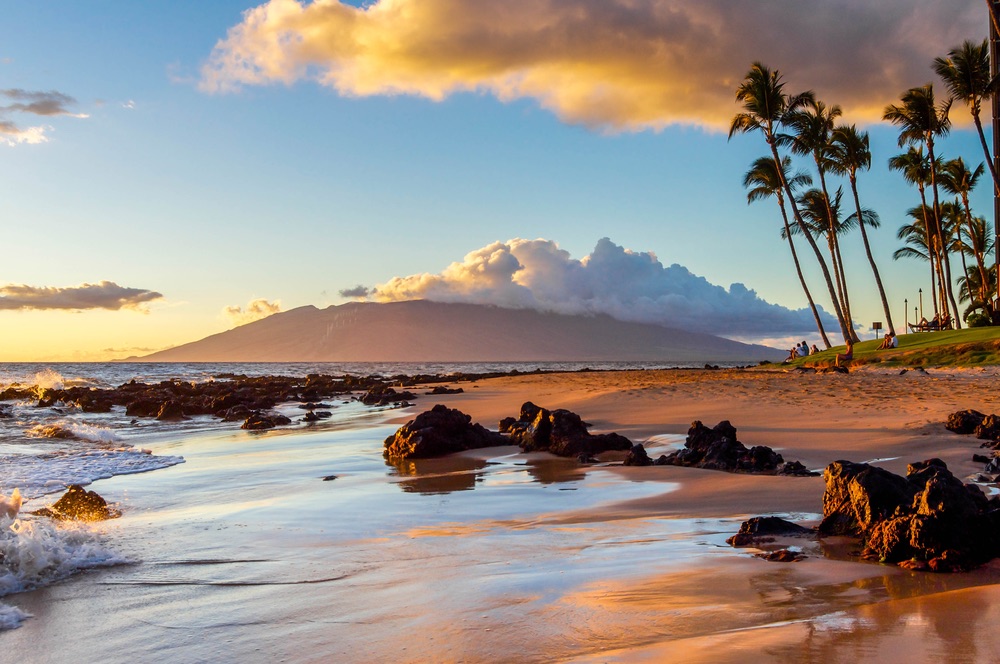 The sunset creates a warm glow on a beach in Maui, Hawaii