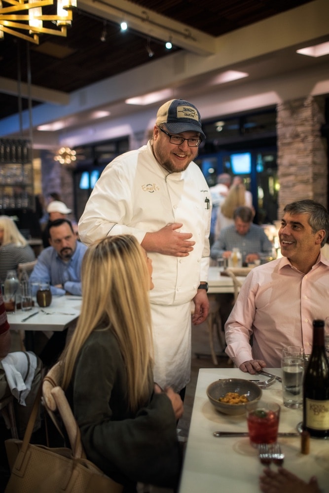 Chef at Emeril’s Coastal Italian at Grand Boulevard in Miramar Beach, Florida talking with a couple at their table