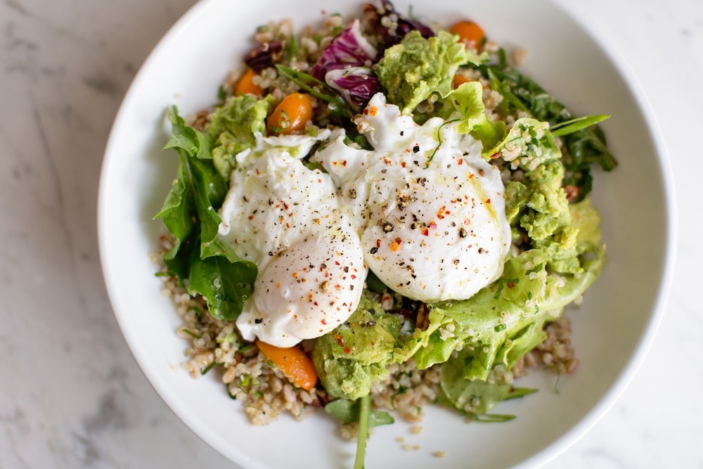 A healthy salad with avocado and a pouched egg.