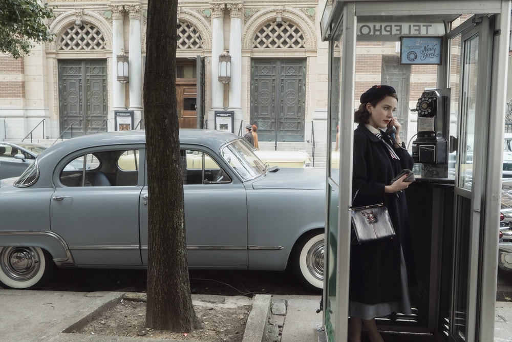 Midge Maisel talking on the phone in a phone booth