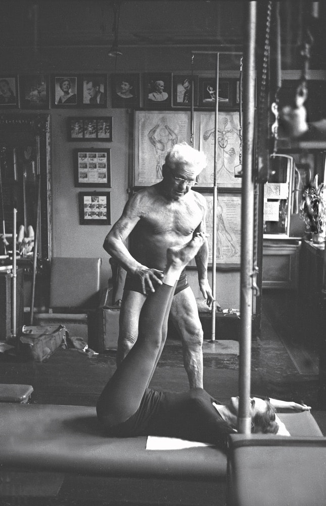 Pilates exercise system founder Joseph Pilates (standing) works with a client at his Eighth Avenue gym in New York City on October 4, 1961.