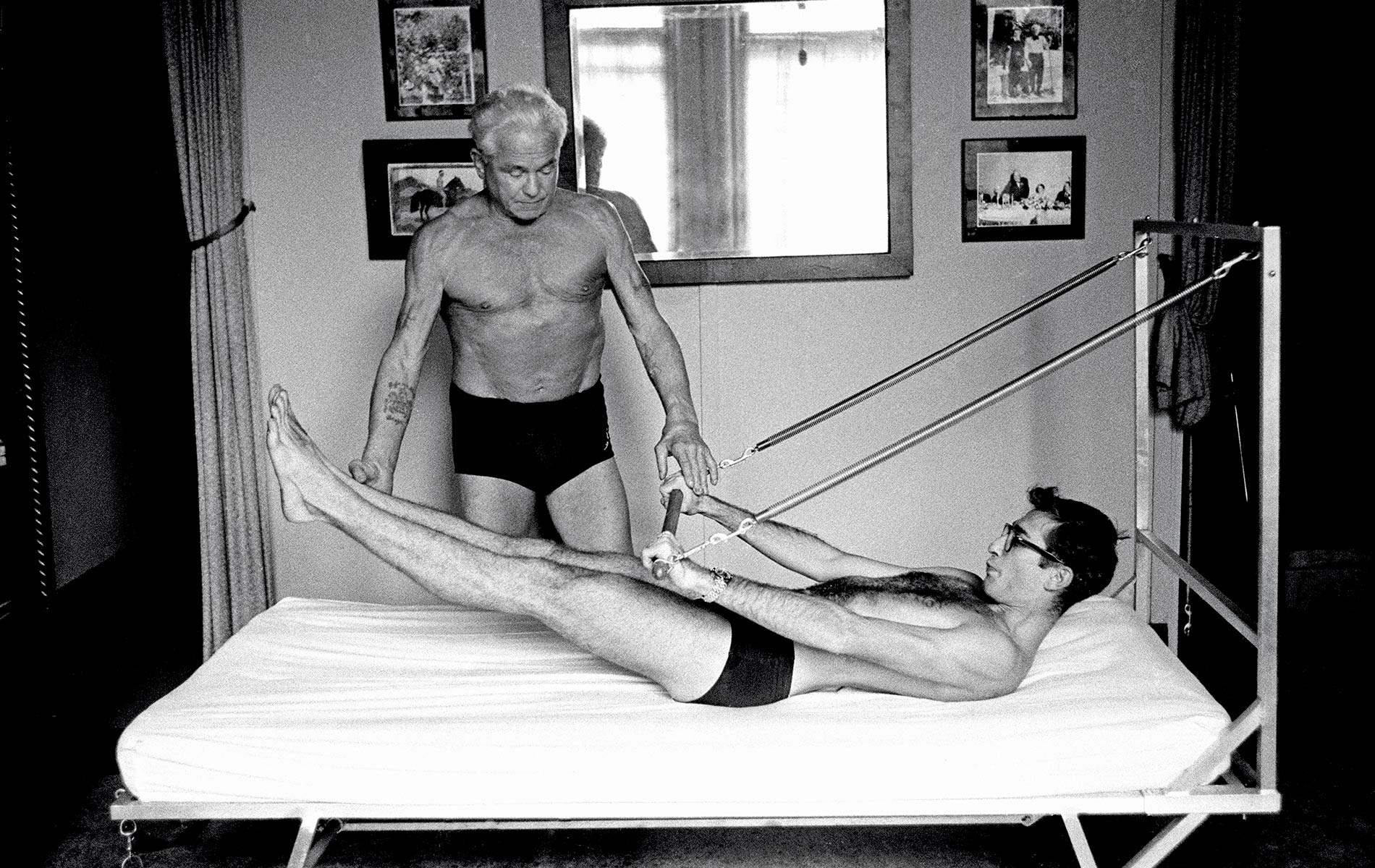 Joseph Pilates offers photographer Chuck “I.C.” Rapoport a firsthand demonstration of his Bednasium machine on October 4, 1961.