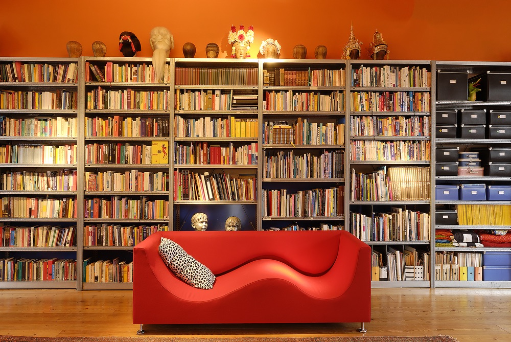 Large, orange library wall and a cozy, red couch make up a big portion of the family's living room in The Blue House.