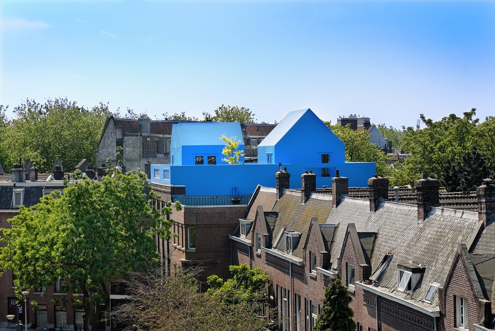 A rooftop view of The Blue House and its neighboring houses shows just how bright the blue stands out among the neutral shades of other houses on the street.