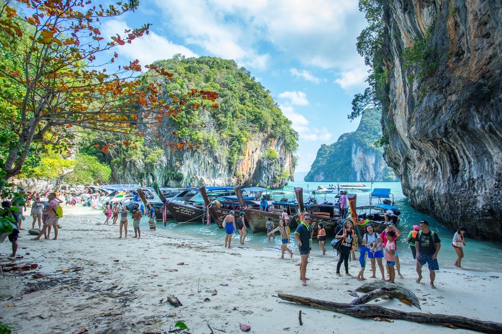 People arriving on an island by long tail boat and speed boat in Krabi Province Thailand.