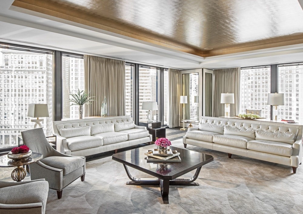 Regent Suite Parlor at the Langham Hotel with walls full of windows to view downtown Chicago, decorated with gold and cream details.