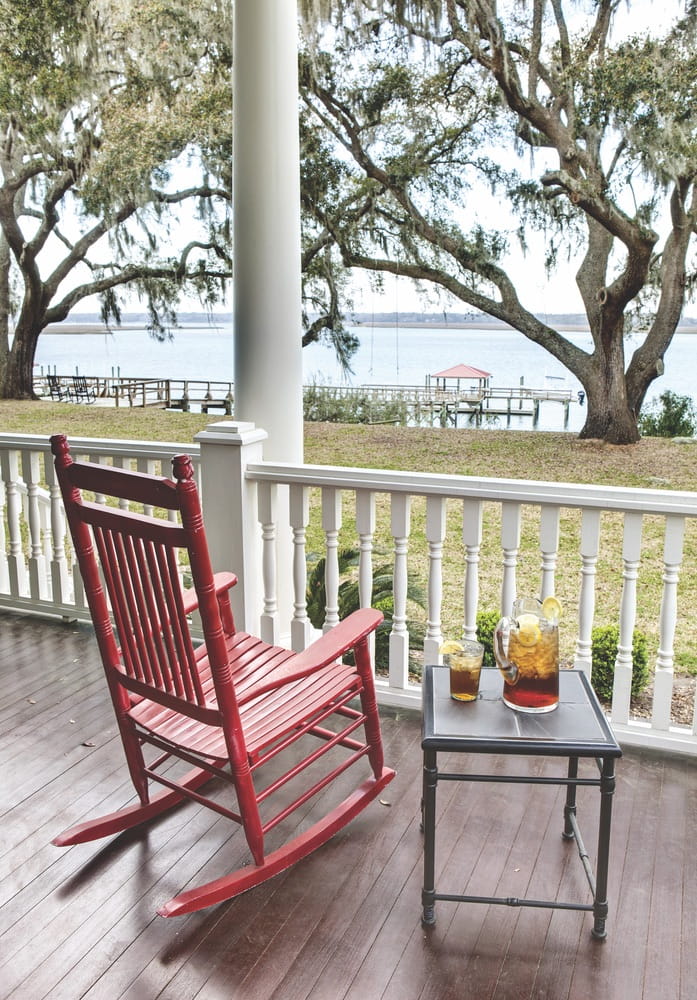 Red rocking chair and table with iced tea with waterfront view