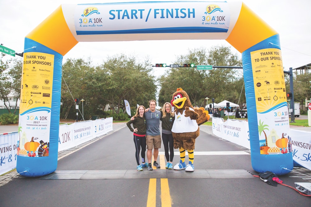 Co-race director Craig Baranowski (center) of Scenic Sotheby’s International Realty stands in the Rosemary Beach intersection of Highway 30-A with 30A 10K Thanksgiving Day founders, Karen Meadows (right) and Amy Stoyles (left), at the 2017 race.