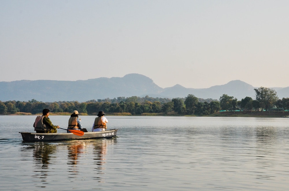 Trio of people in a boat in India searching for tigers