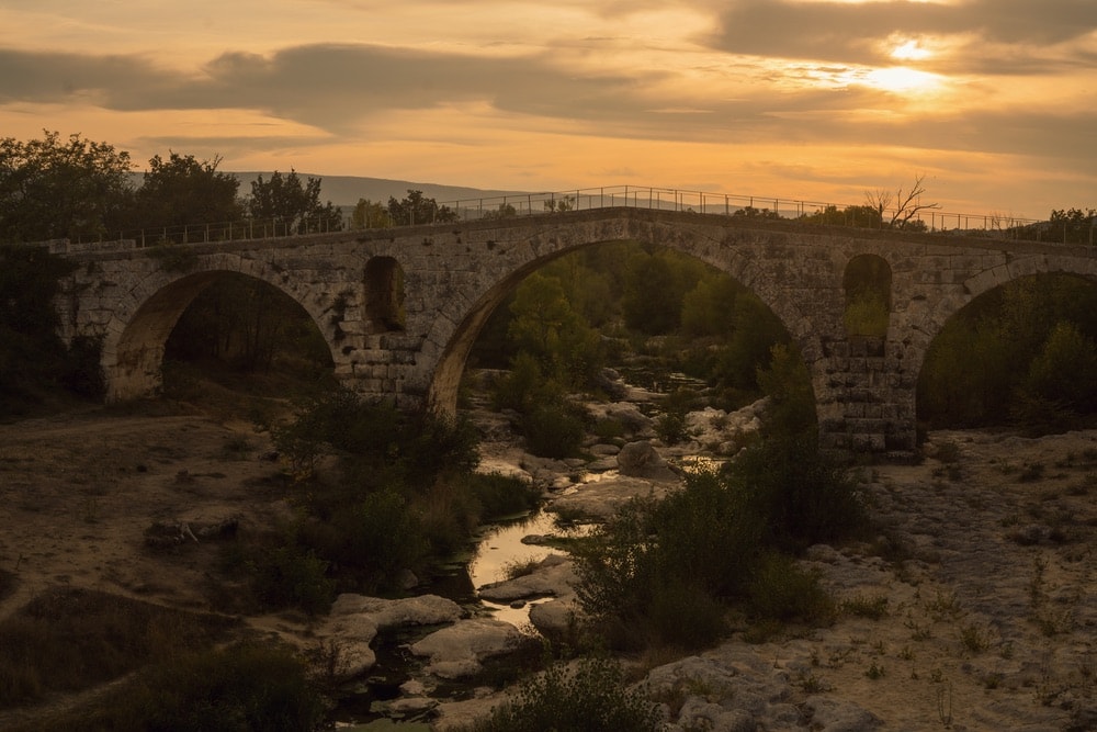 Photograph by Jamie Beck showing an older, brick bridge in Provence France at dusk