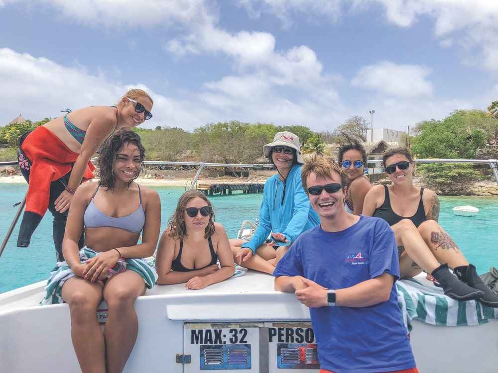 Divemaster Loys, Michelle, Stephanie, Romona, Divemaster Floris, Rana, and Breanna take a break after exploring the western side of the island with Go West Diving